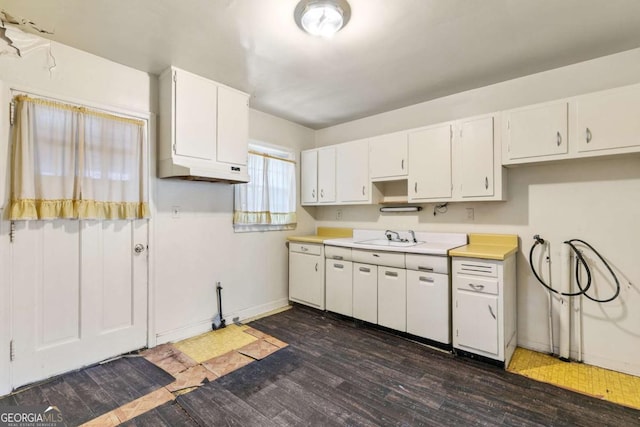 kitchen featuring dark wood-style floors, baseboards, a sink, light countertops, and white cabinetry