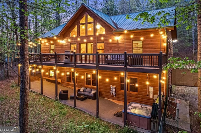 back of property featuring outdoor lounge area, a wooden deck, a patio area, and metal roof