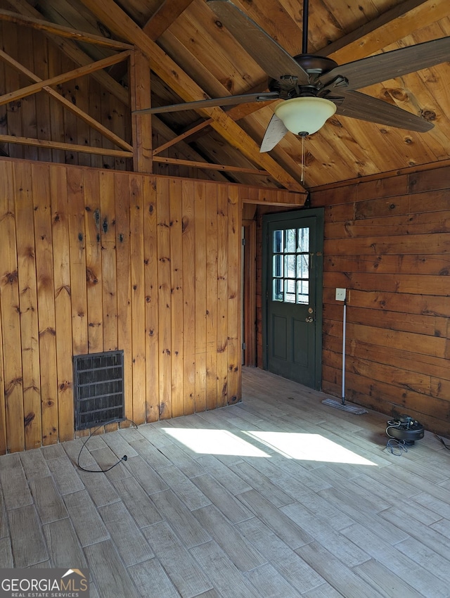 spare room with lofted ceiling with beams, wood ceiling, ceiling fan, and wood walls