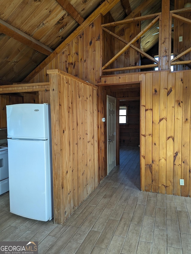 kitchen featuring white appliances, lofted ceiling, wood finished floors, and wood walls