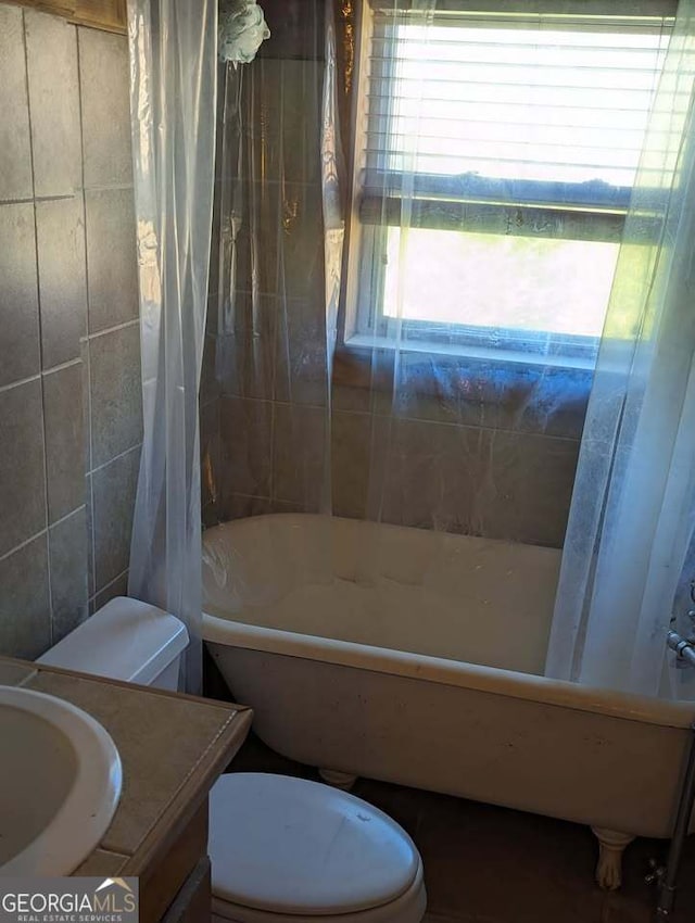 bathroom featuring toilet, tile walls, shower / bath combo, and vanity