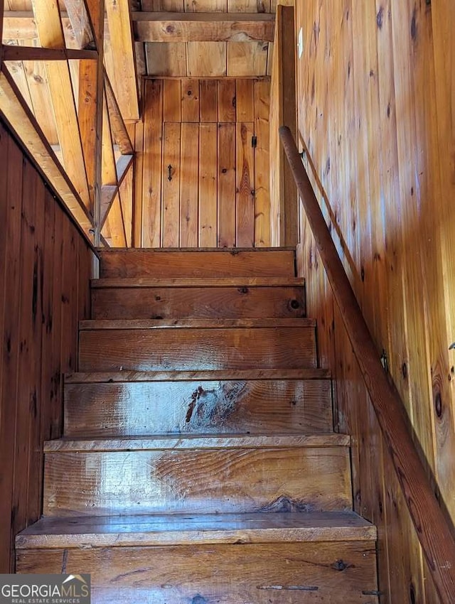 staircase featuring wooden walls