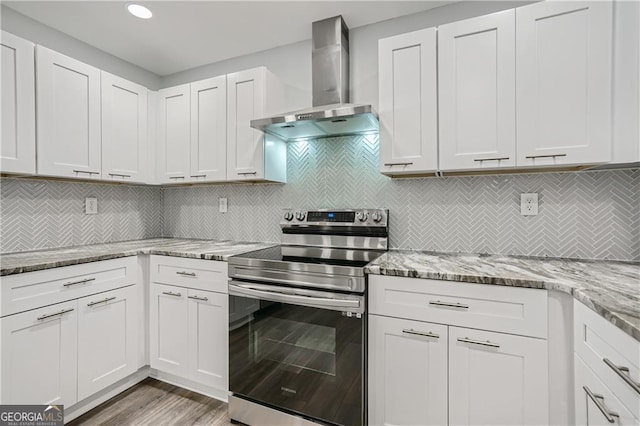 kitchen featuring stainless steel range with electric stovetop, light stone counters, backsplash, wood finished floors, and wall chimney exhaust hood