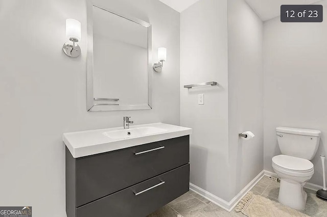 half bathroom with toilet, vanity, and baseboards