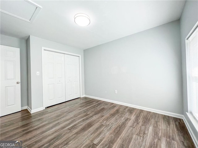 unfurnished bedroom featuring wood finished floors, a closet, and baseboards