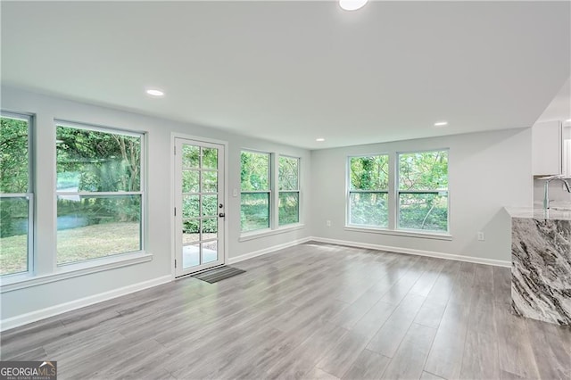 unfurnished living room with light wood finished floors, recessed lighting, baseboards, and a sink