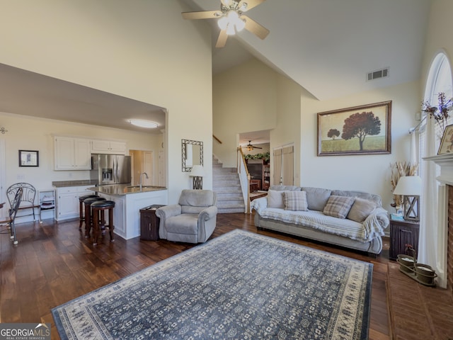 living room with visible vents, dark wood-style flooring, ceiling fan, and stairs