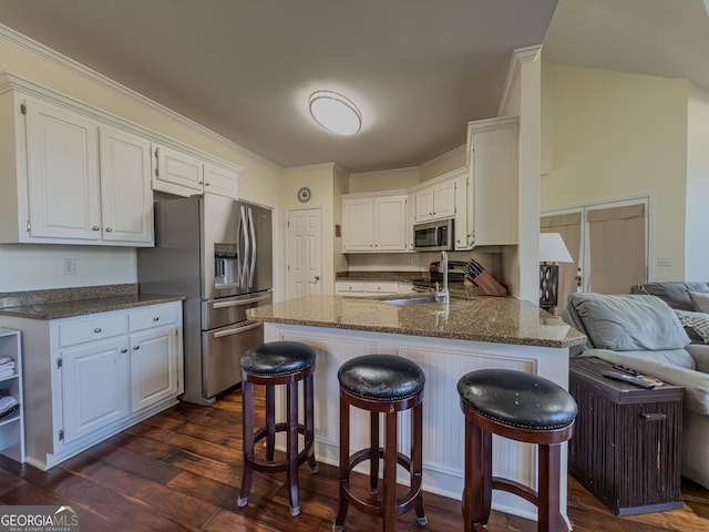 kitchen featuring dark wood-style floors, a peninsula, a sink, appliances with stainless steel finishes, and white cabinetry