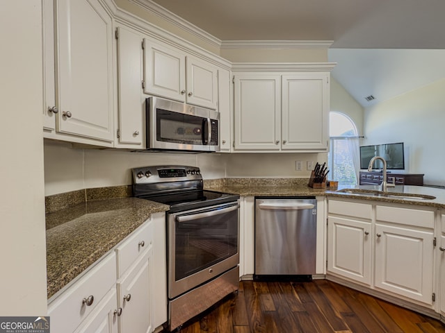 kitchen featuring dark stone countertops, dark wood-style flooring, a sink, white cabinets, and appliances with stainless steel finishes