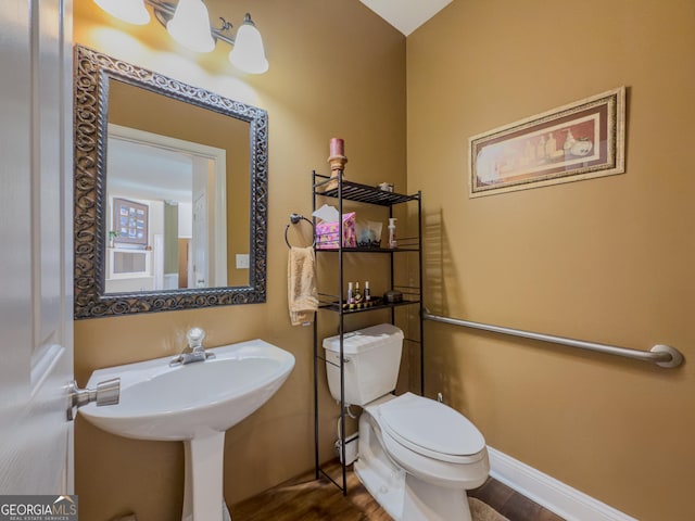 half bathroom featuring toilet, wood finished floors, and baseboards