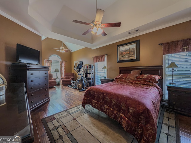 bedroom with a ceiling fan, wood finished floors, visible vents, a tray ceiling, and ornamental molding