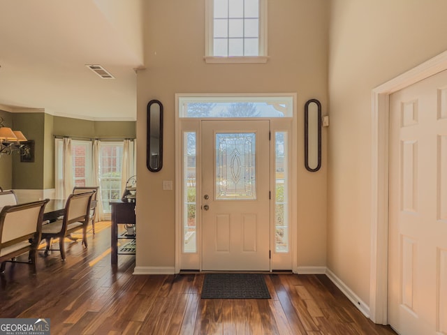 entryway featuring dark wood-style floors, visible vents, baseboards, and a towering ceiling