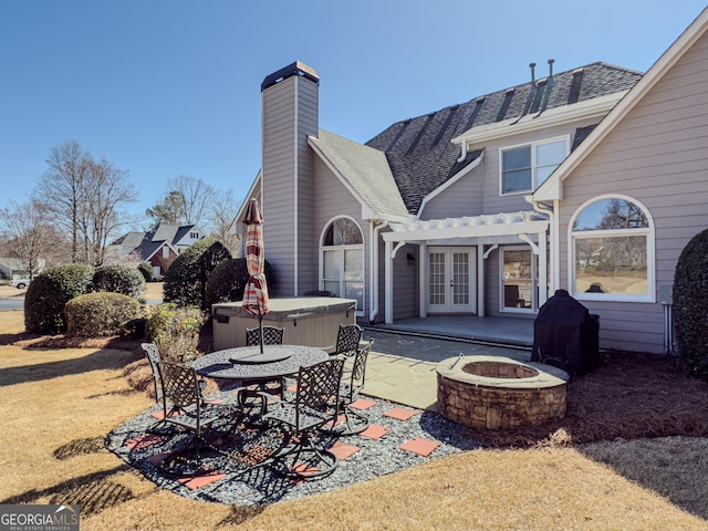 rear view of property with a hot tub, roof with shingles, french doors, a patio area, and a pergola