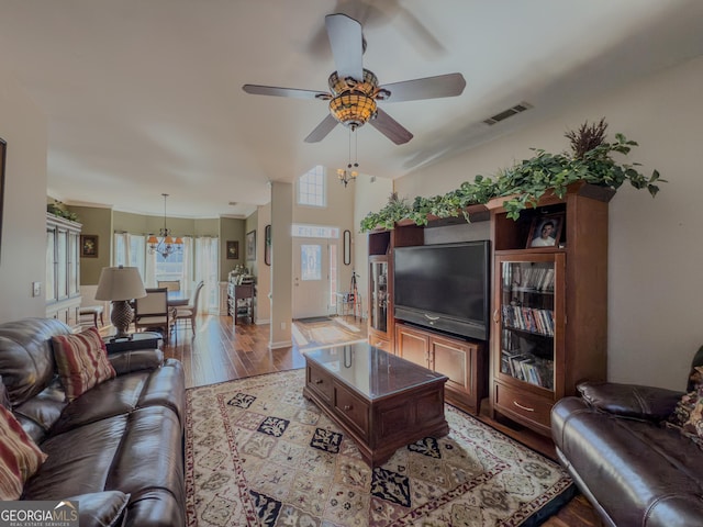 living area with visible vents, light wood-style flooring, and ceiling fan with notable chandelier