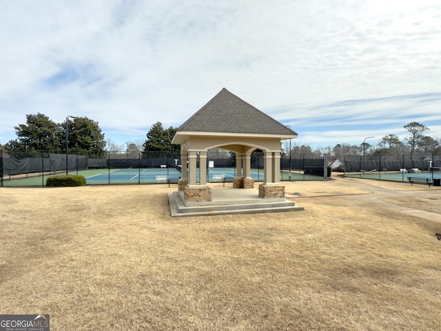 surrounding community with a tennis court and fence