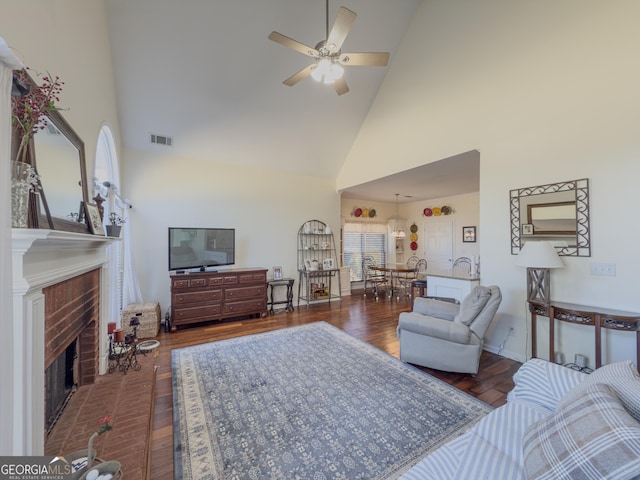 living area featuring visible vents, high vaulted ceiling, a brick fireplace, ceiling fan, and dark wood-style flooring