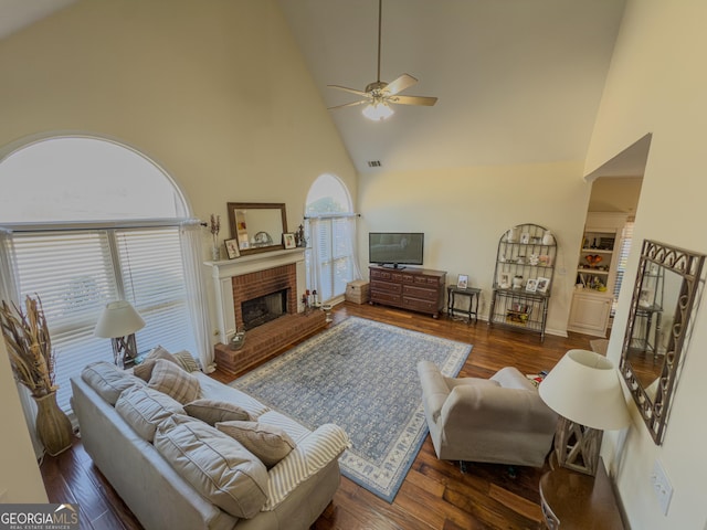 living room with visible vents, a brick fireplace, ceiling fan, wood finished floors, and high vaulted ceiling