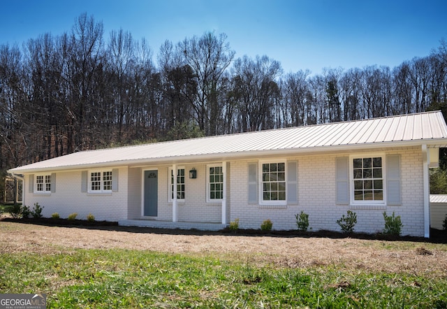 ranch-style house featuring brick siding, a porch, and metal roof