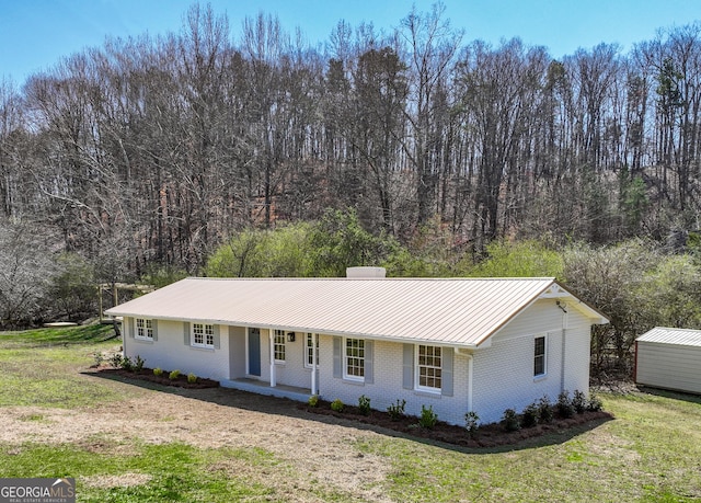 ranch-style house with brick siding, a porch, a front yard, a chimney, and metal roof