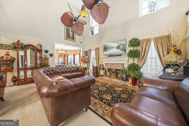 living room with carpet, visible vents, a towering ceiling, a brick fireplace, and a chandelier