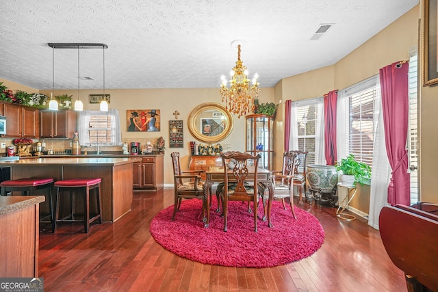 dining room with an inviting chandelier, visible vents, dark wood-type flooring, and a textured ceiling