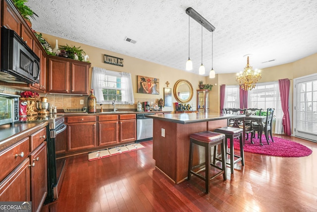 kitchen with dark wood-type flooring, visible vents, appliances with stainless steel finishes, and a chandelier