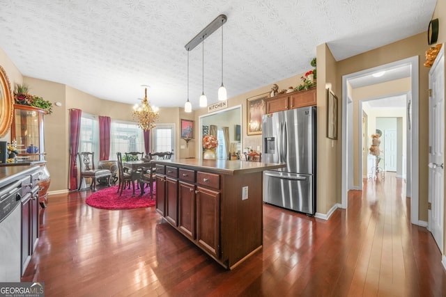 kitchen featuring a kitchen island, decorative light fixtures, appliances with stainless steel finishes, an inviting chandelier, and dark wood-style flooring