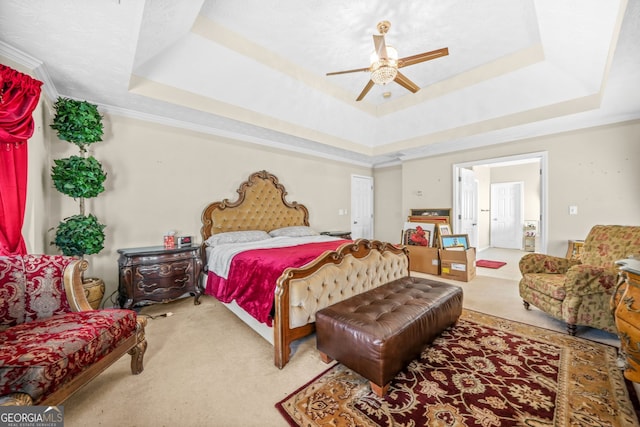 bedroom featuring a raised ceiling, a ceiling fan, carpet floors, and ornamental molding