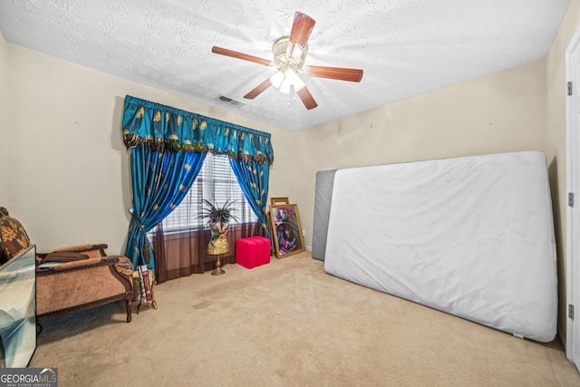 bedroom with carpet flooring, a ceiling fan, visible vents, and a textured ceiling