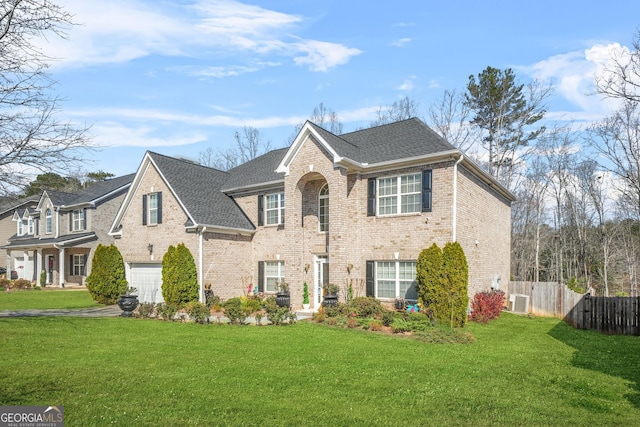 view of front facade featuring a front lawn, an attached garage, fence, and brick siding