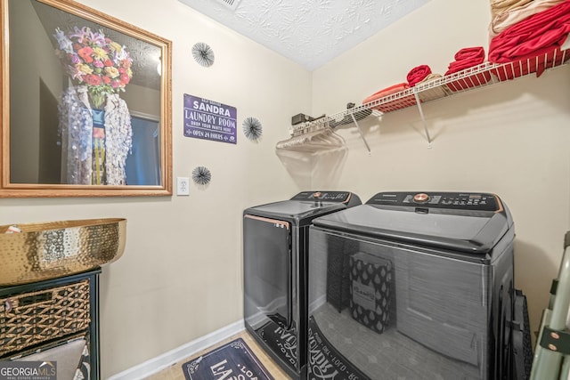 washroom featuring laundry area, baseboards, independent washer and dryer, and a textured ceiling