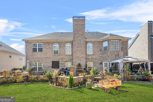 rear view of house featuring a gazebo, a yard, a patio, and brick siding