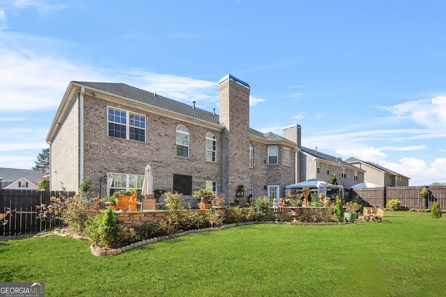 back of property featuring a lawn, a chimney, a patio, and fence