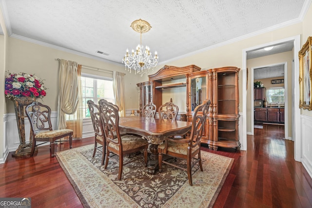 dining area with visible vents, wainscoting, dark wood-type flooring, a textured ceiling, and a chandelier