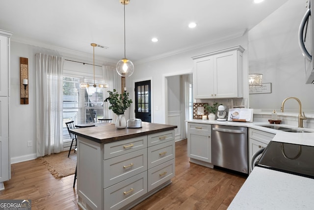 kitchen featuring dishwasher, ornamental molding, a sink, butcher block countertops, and a notable chandelier