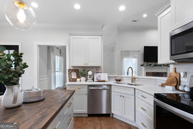 kitchen with crown molding, appliances with stainless steel finishes, a sink, and wooden counters