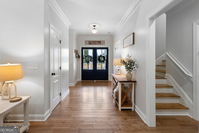 foyer featuring light wood-style flooring, baseboards, stairway, and crown molding