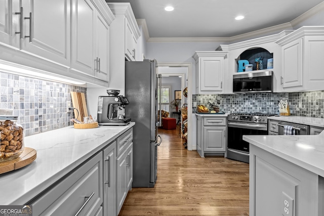 kitchen with stainless steel appliances, light wood-style floors, crown molding, and white cabinetry