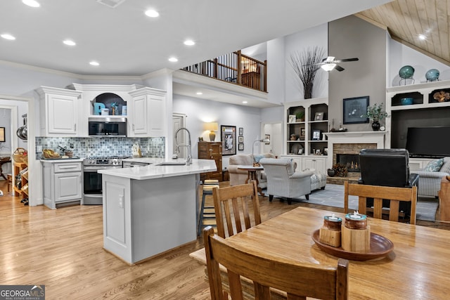 dining area featuring ornamental molding, a ceiling fan, recessed lighting, a fireplace, and light wood finished floors