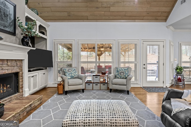 living room with visible vents, wood ceiling, vaulted ceiling, a stone fireplace, and dark wood-style floors