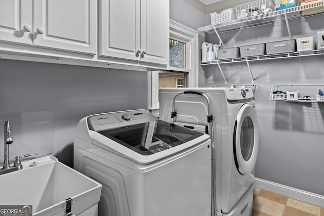 laundry area with cabinet space, washing machine and dryer, baseboards, and a sink