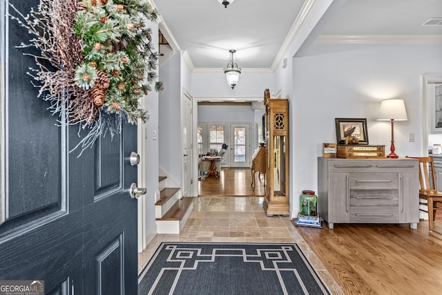 foyer entrance featuring crown molding, light wood-style flooring, and visible vents