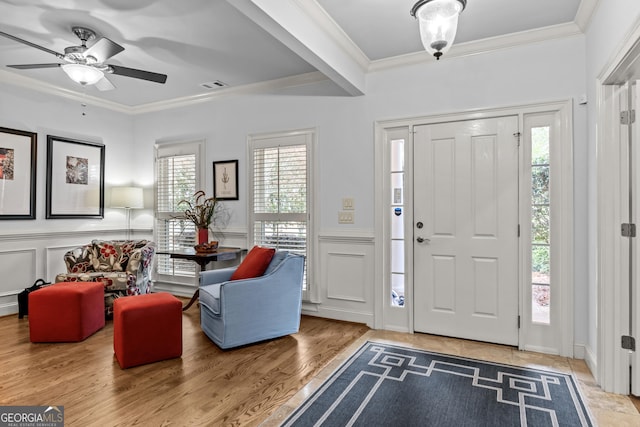 entryway with a decorative wall, visible vents, crown molding, and a ceiling fan