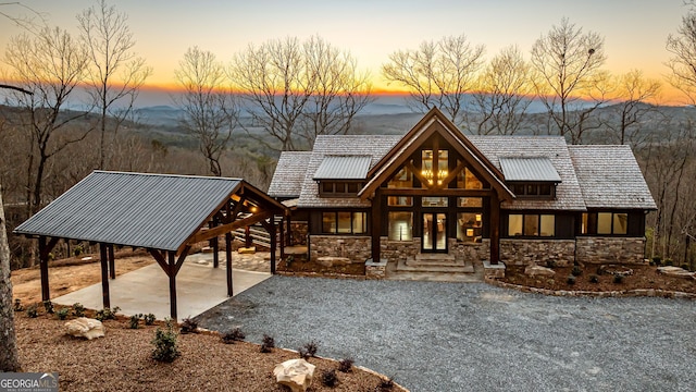 view of front facade featuring french doors, stone siding, and a patio area