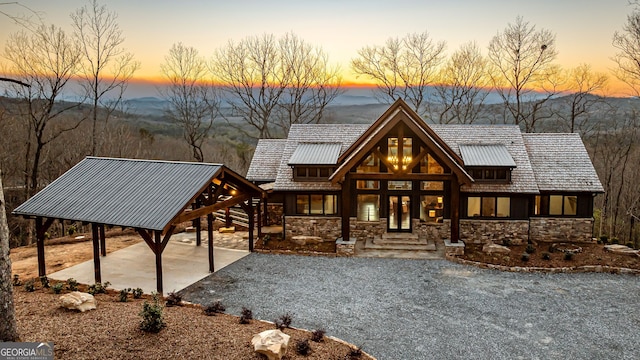 view of front facade featuring french doors, stone siding, and a patio area