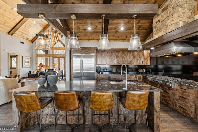 kitchen with a sink, stainless steel appliances, a large island, wood ceiling, and wall chimney exhaust hood