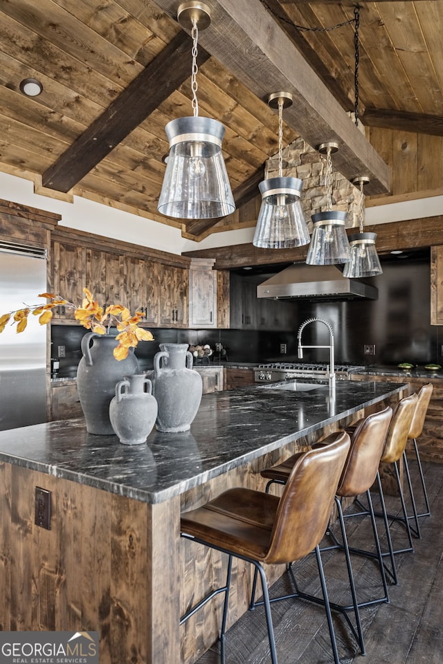 kitchen featuring beamed ceiling, wooden ceiling, a kitchen breakfast bar, a large island, and wall chimney exhaust hood