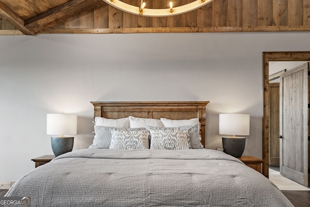 bedroom with wood finished floors and vaulted ceiling with beams