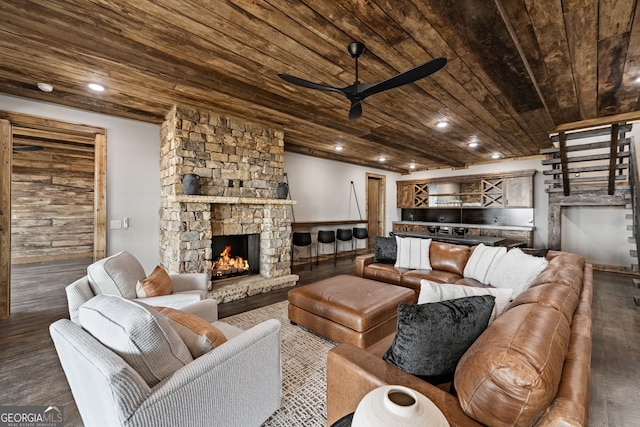 living room featuring wood ceiling, a stone fireplace, dark wood-style flooring, and a ceiling fan