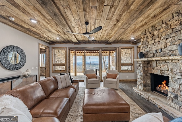 living room with a ceiling fan, wood finished floors, recessed lighting, a stone fireplace, and wooden ceiling